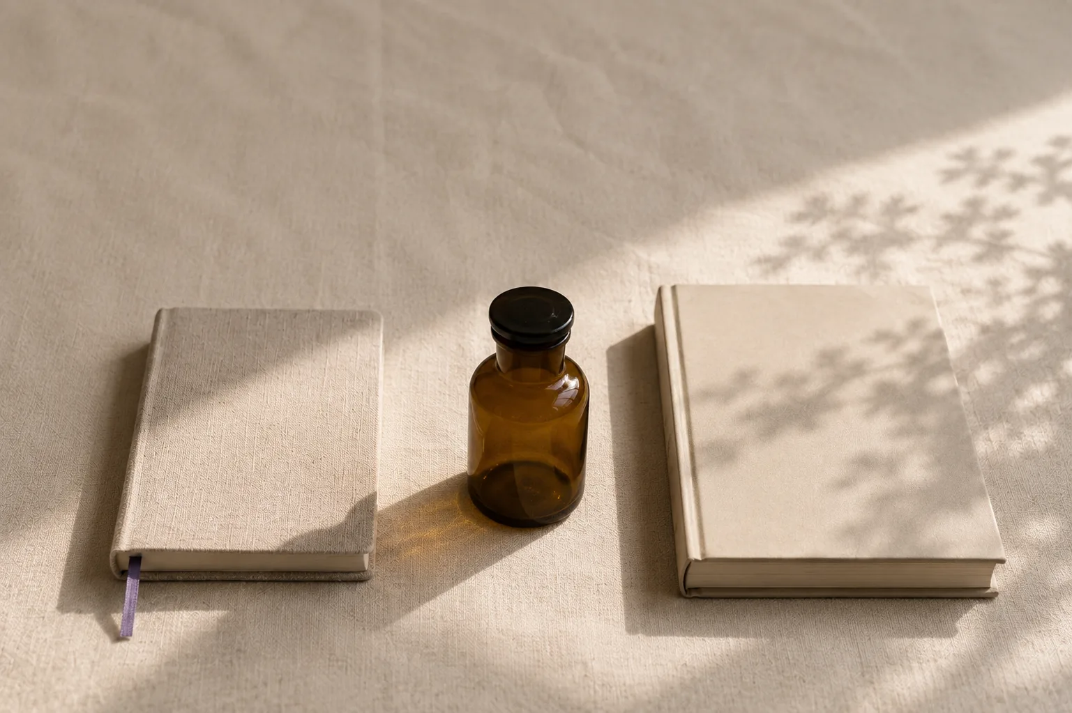 Libros junto a un frasco de vidrio ámbar, con luz cálida de ventana