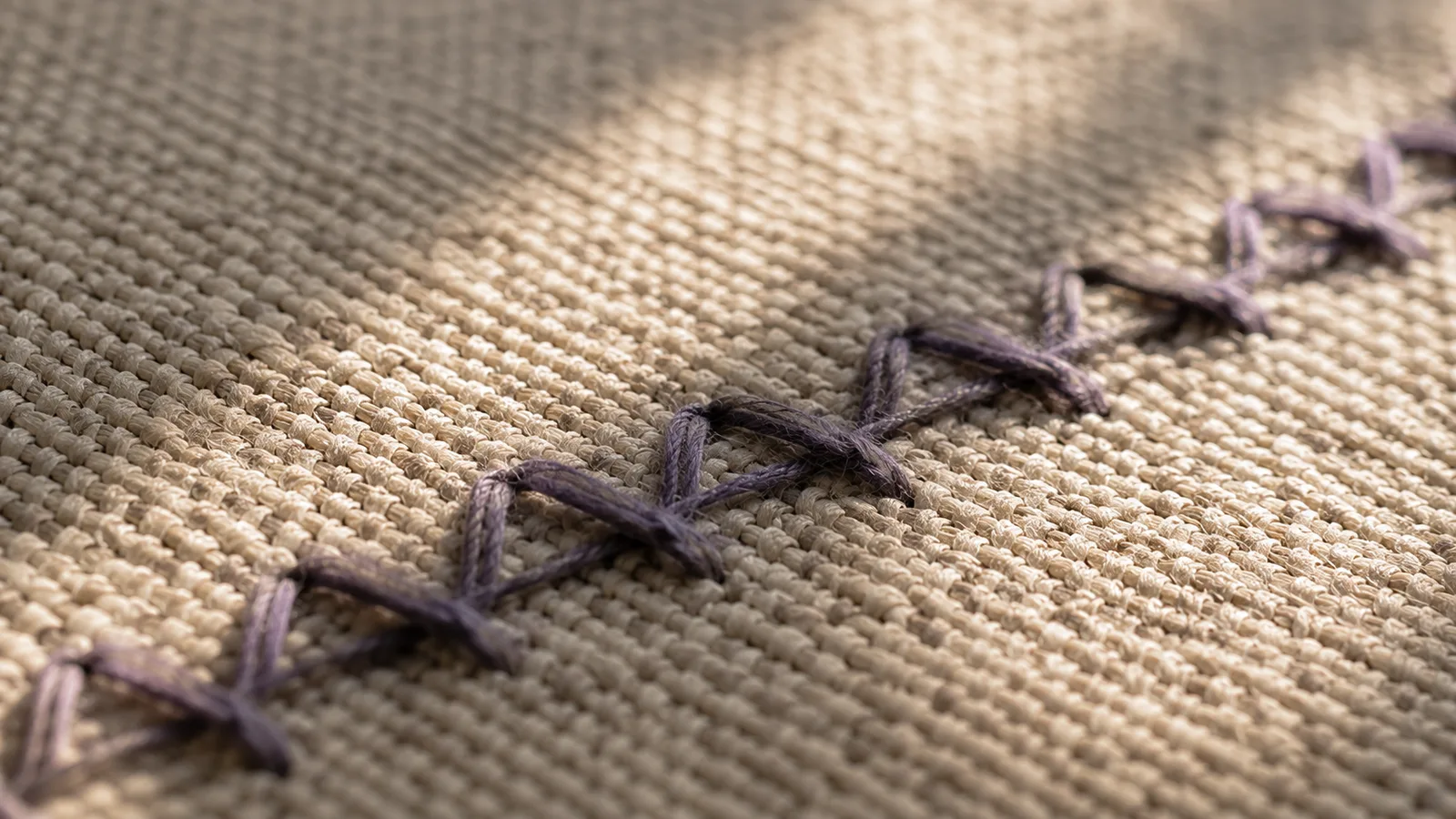 Costura en zigzag sobre tela tejida, en tonos crema y lavanda