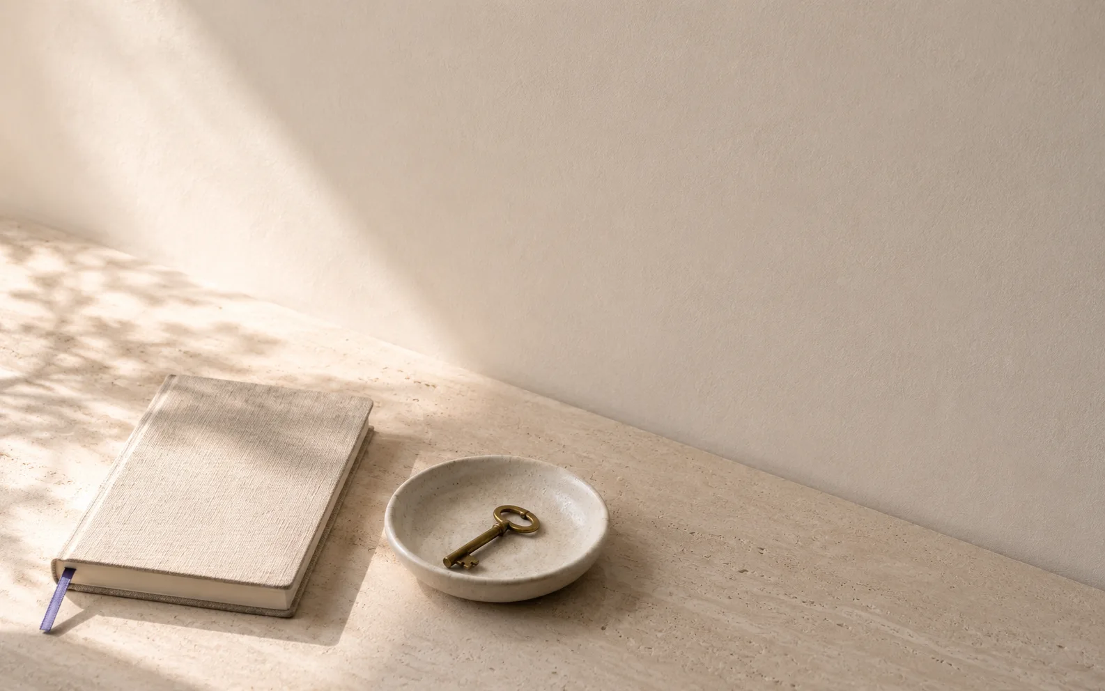 Un libro cerrado junto a un plato con una llave antigua, con luz de sol